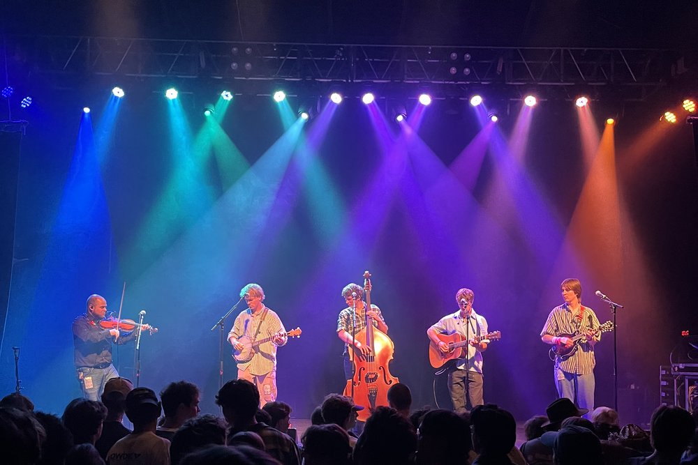 The band on stage at the Fox Theatre under coloured lights